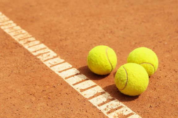 Drei Tennisbälle liegen auf dem Tennisplatz